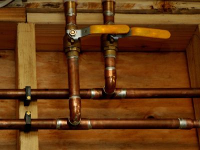 Copper plumbing pipes and valves in a framed wall.