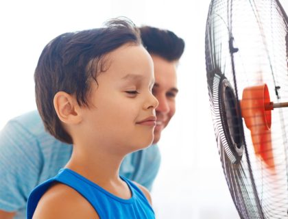 Boy with his dad cooling in front of fan.