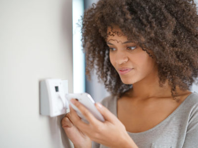 Woman adjusting a thermostat