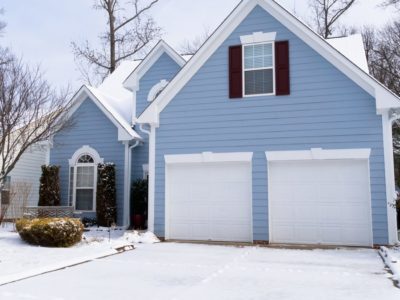 blue house with white garage doors in winter