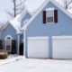 blue house with white garage doors in winter