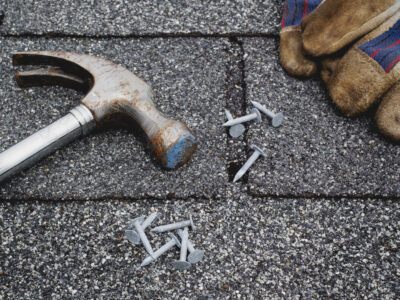 Hammer, roofing nails and work gloves on rooftop shingles