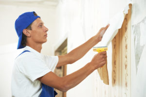 Homeowner peeling wallpaper from a wall