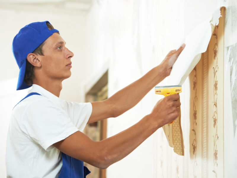 Homeowner peeling wallpaper from a wall