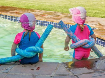 two children sitting at the edge of a pool