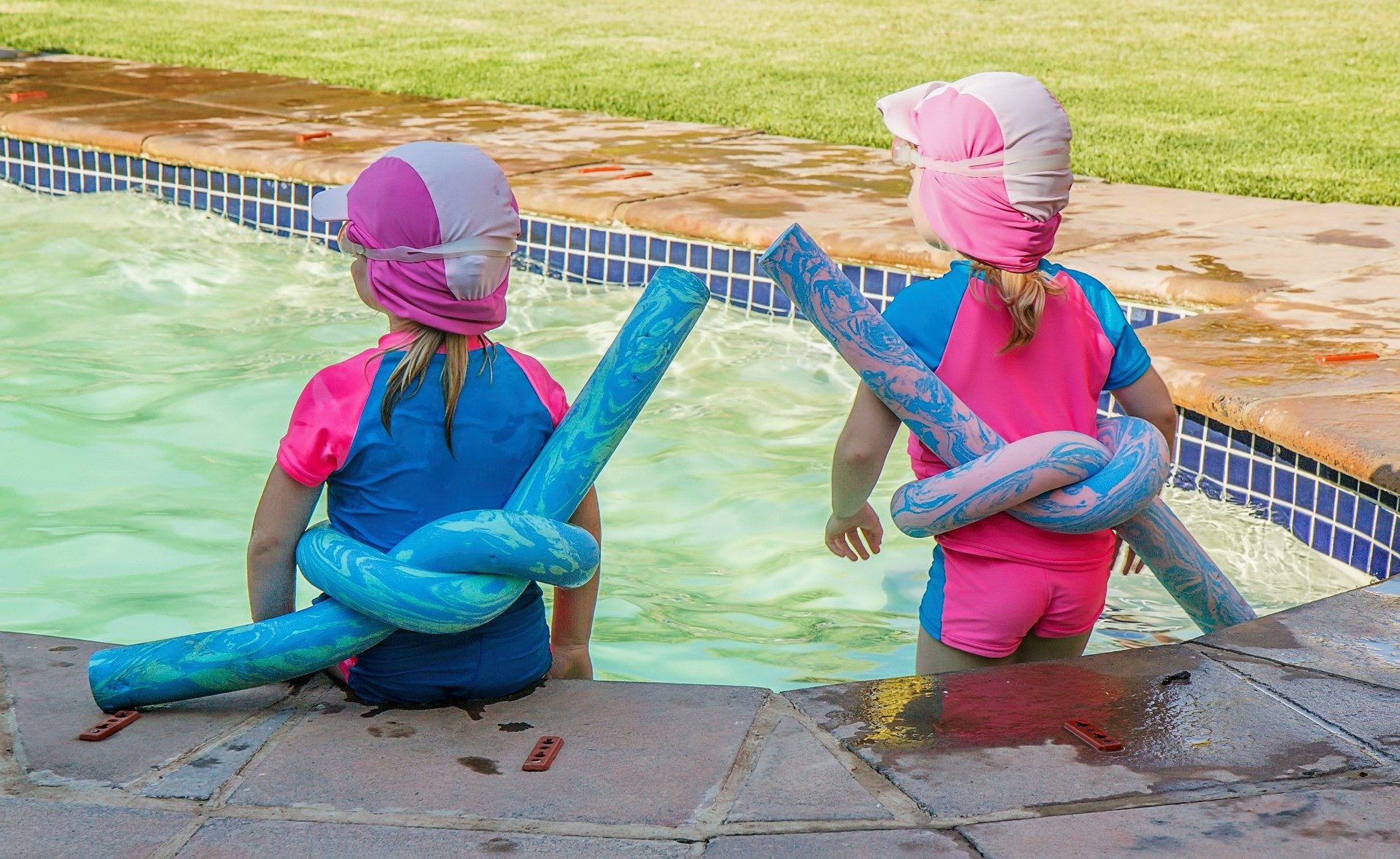 two children sitting at the edge of a pool