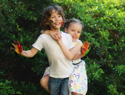 Little kids hugging, their faces and hands are colored