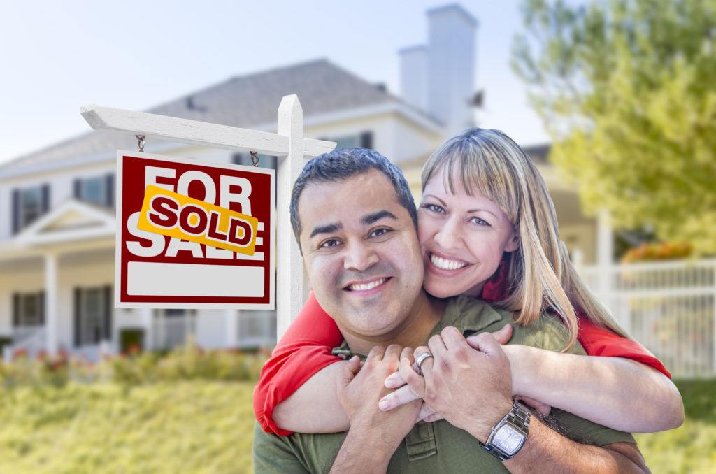 Home sellers happy in front of recently sold home