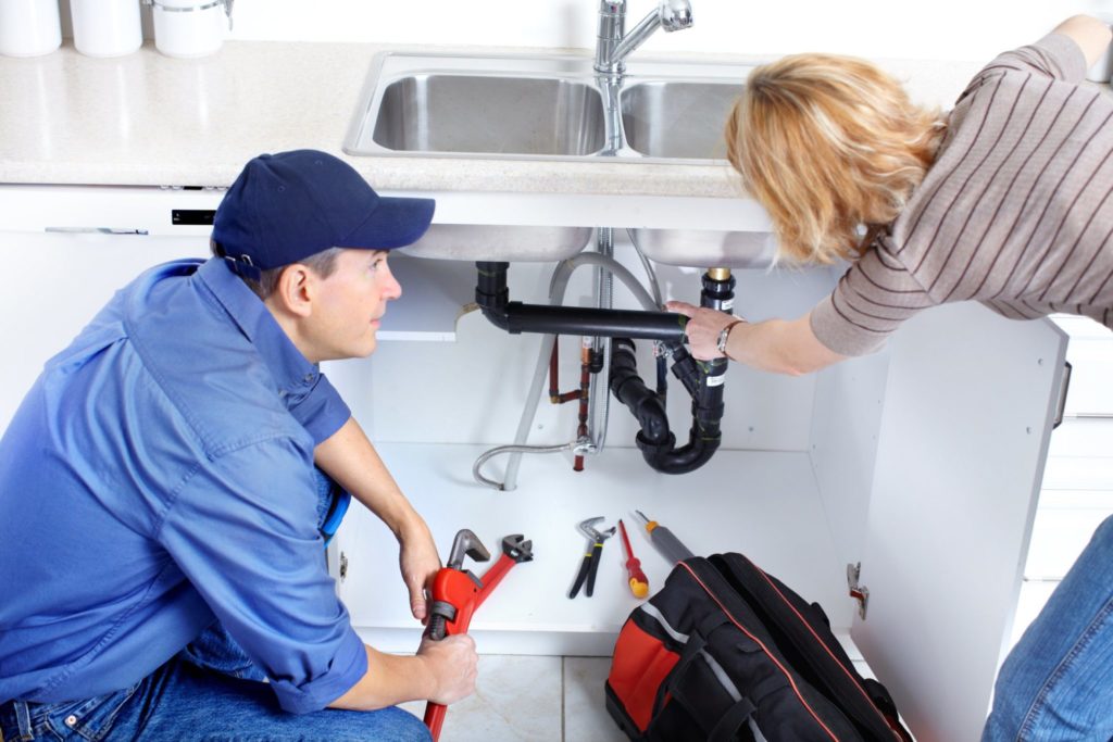 Plumber fixing a sink at kitchen