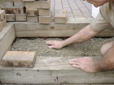 Man building brick paver patio steps