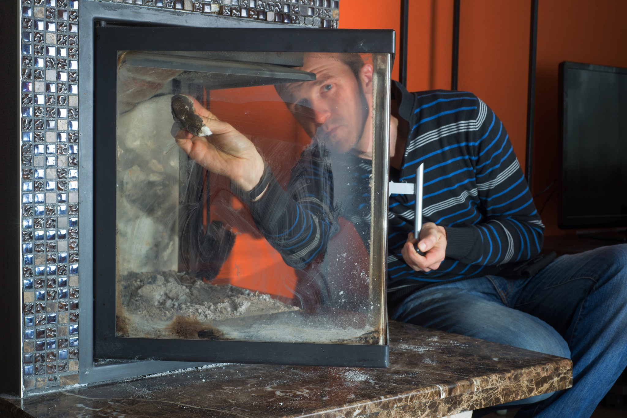 Man wipes the dirty glass of fireplace