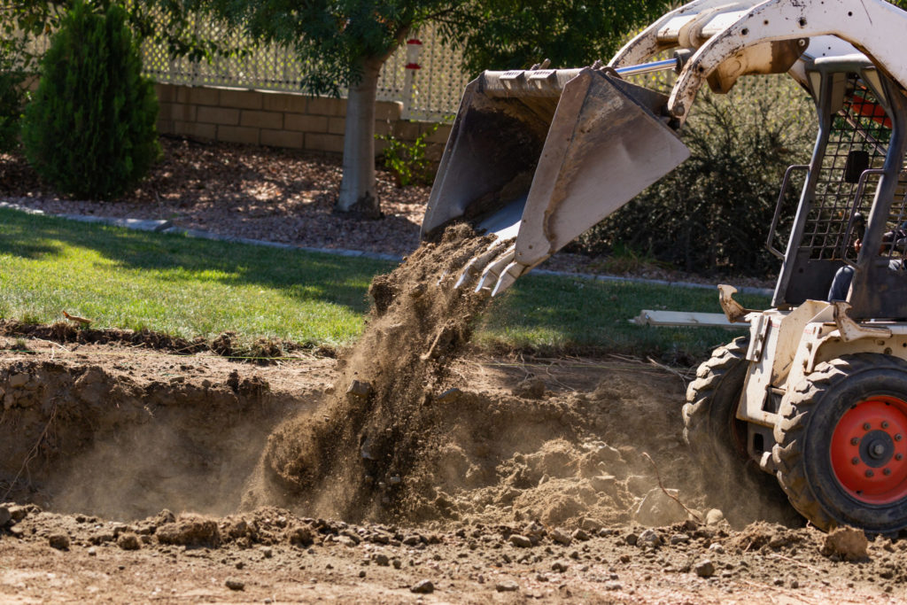 Small bulldozer digging In yard for a spool pool Installation