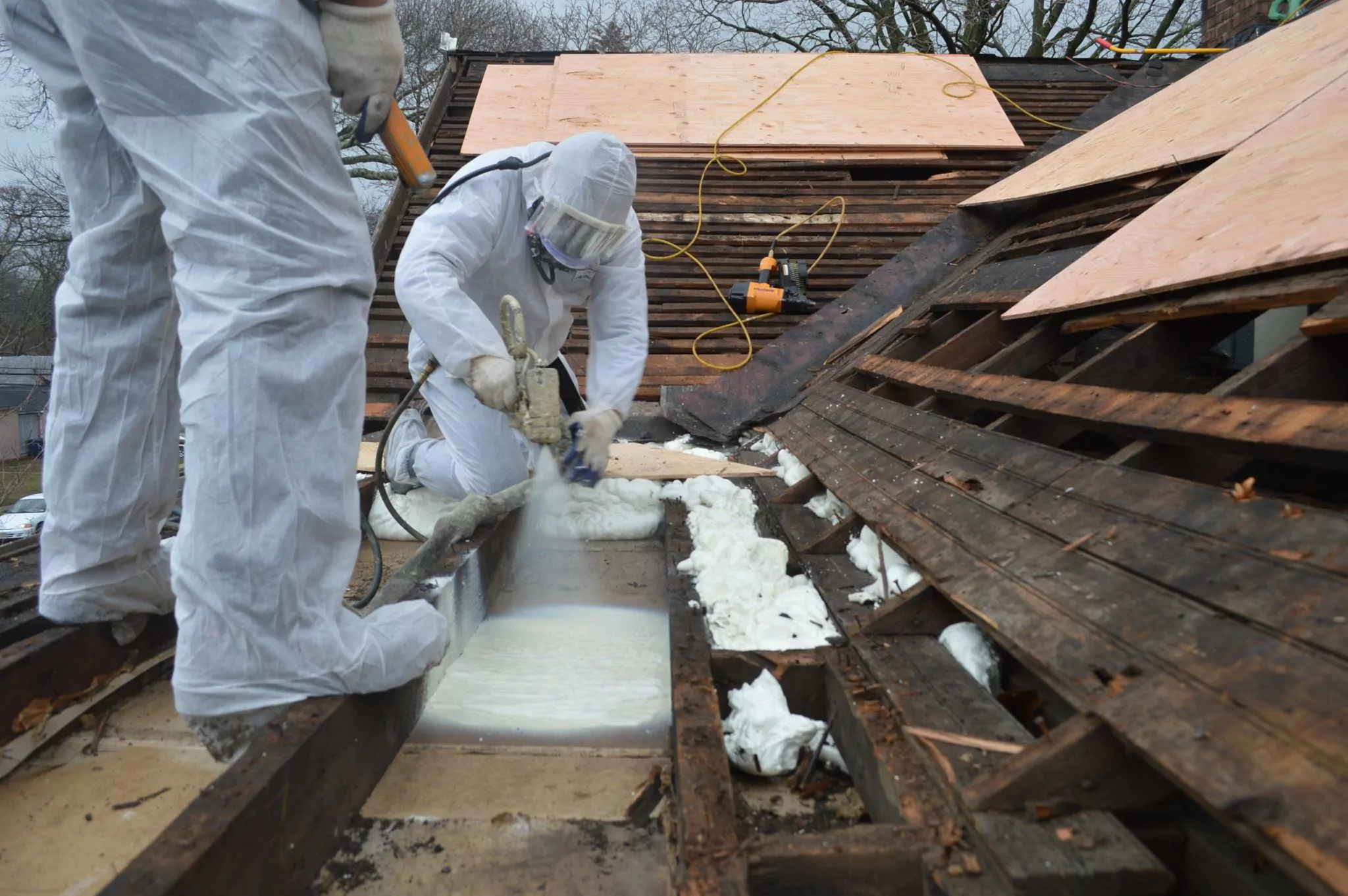 Spray foam is applied to the flat roof section from the outside.