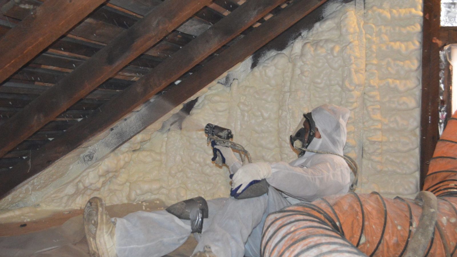 Man applying spray foam in attic