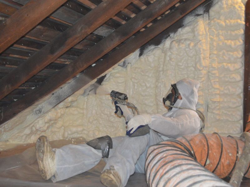 Man applying spray foam in attic
