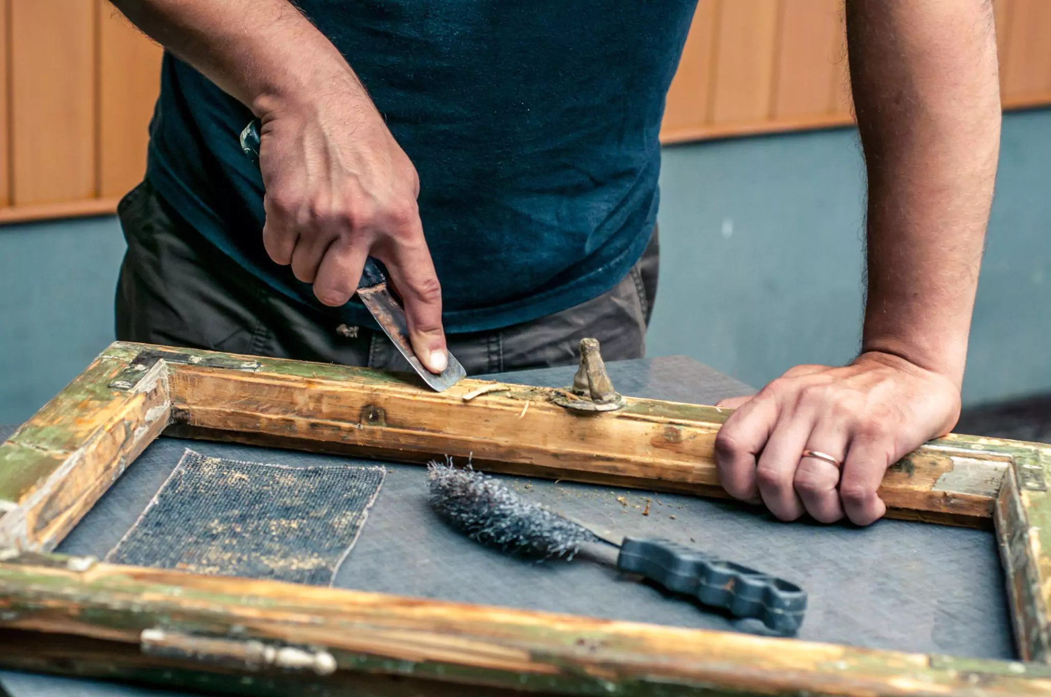 Man removing paint from an old window frame