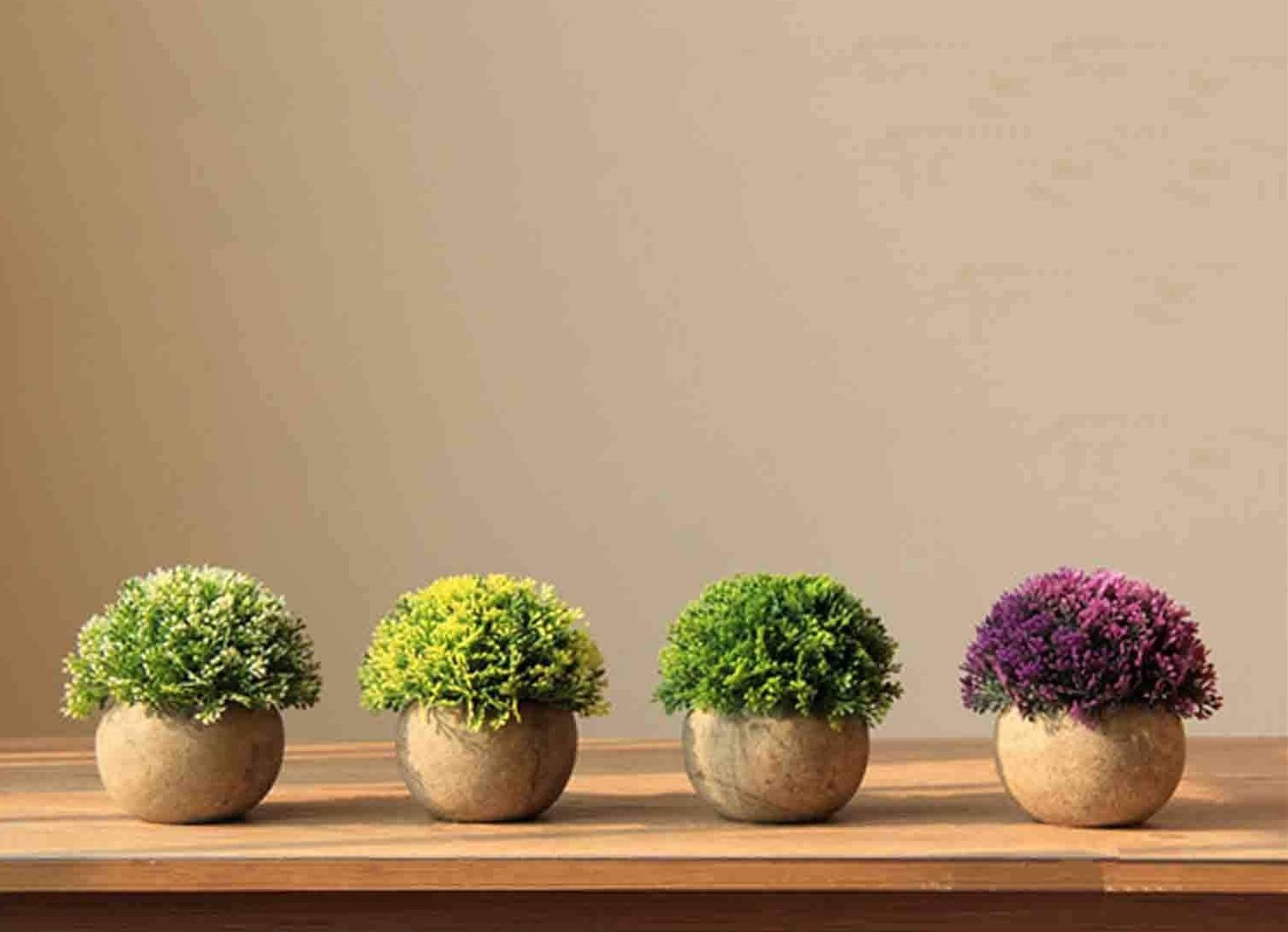 4 artificial, fake, plants on a table.