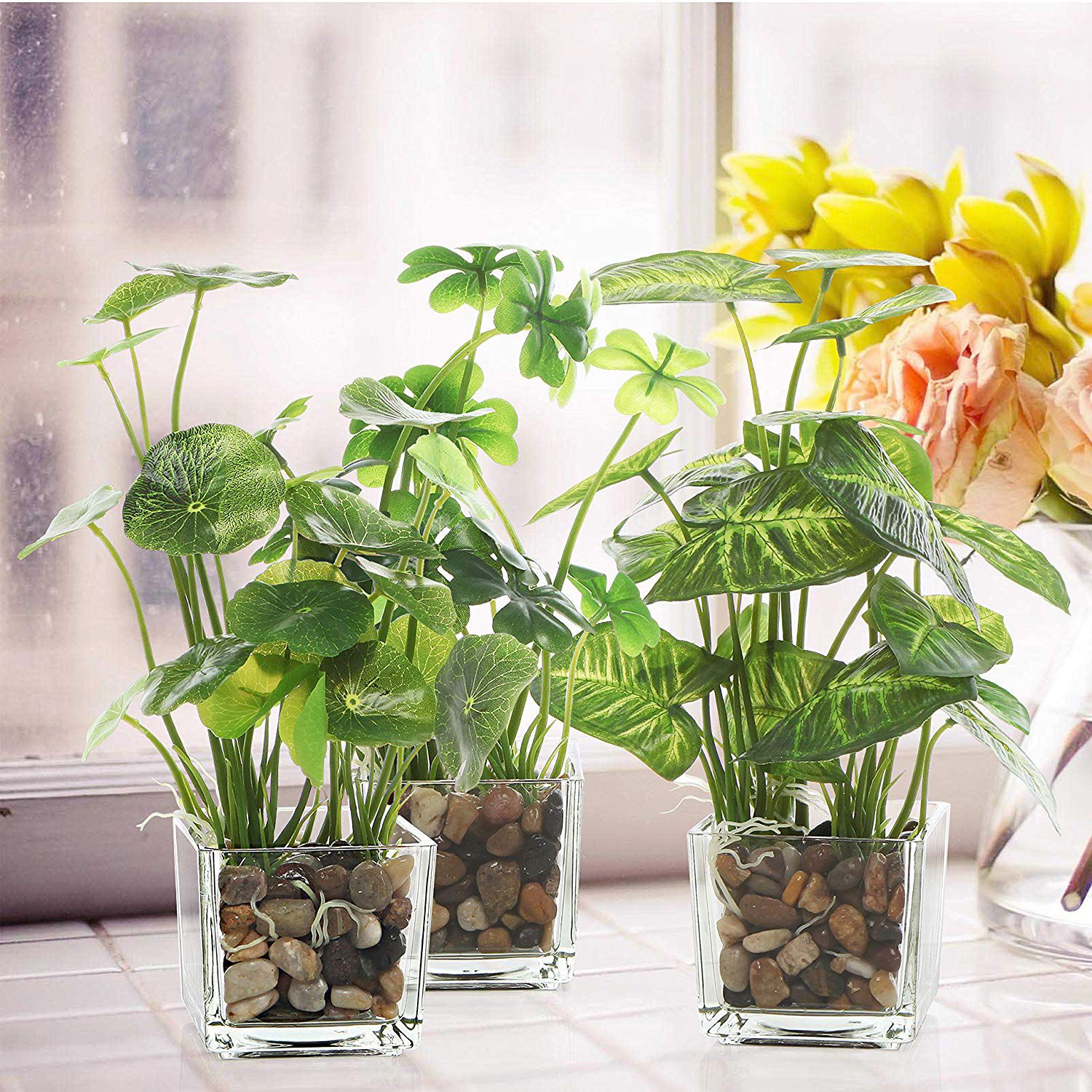 Artificial, fake, plants in clear glass pots near window