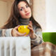 woman with yellow cup near radiator at home