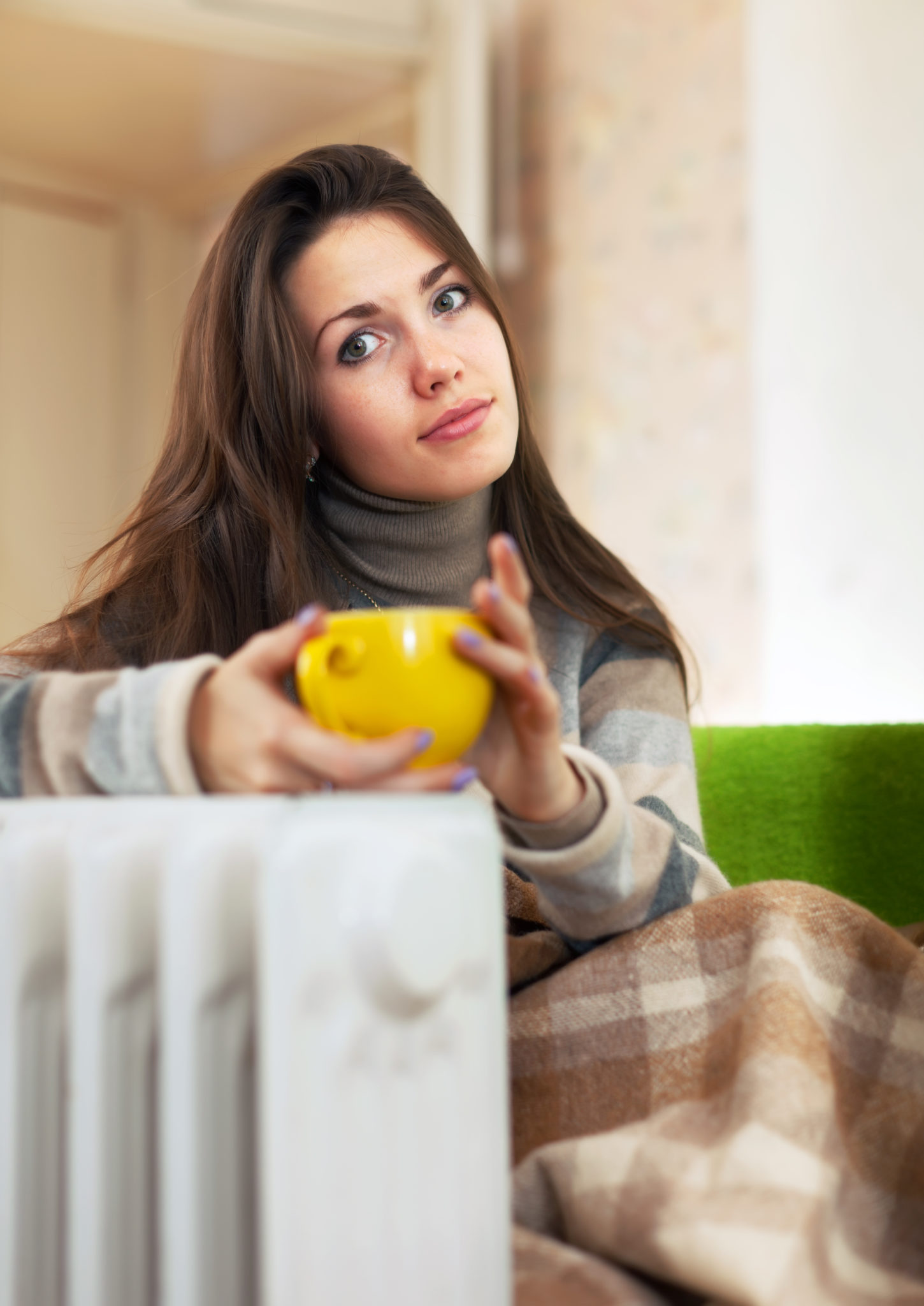 woman with yellow cup near radiator at home