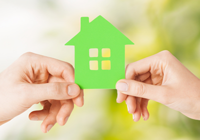 two hands holding small green home puzzle