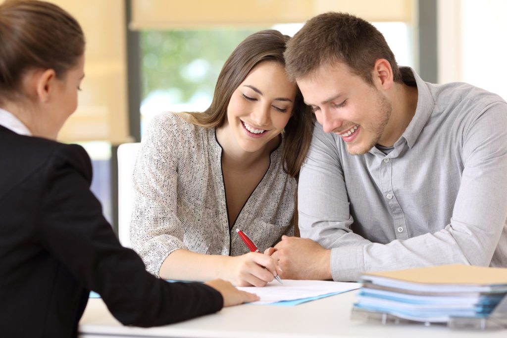 Happy couple signing a contract together for homeowners insurance