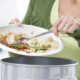 Woman Scraping Food Leftovers Into Garbage Bin