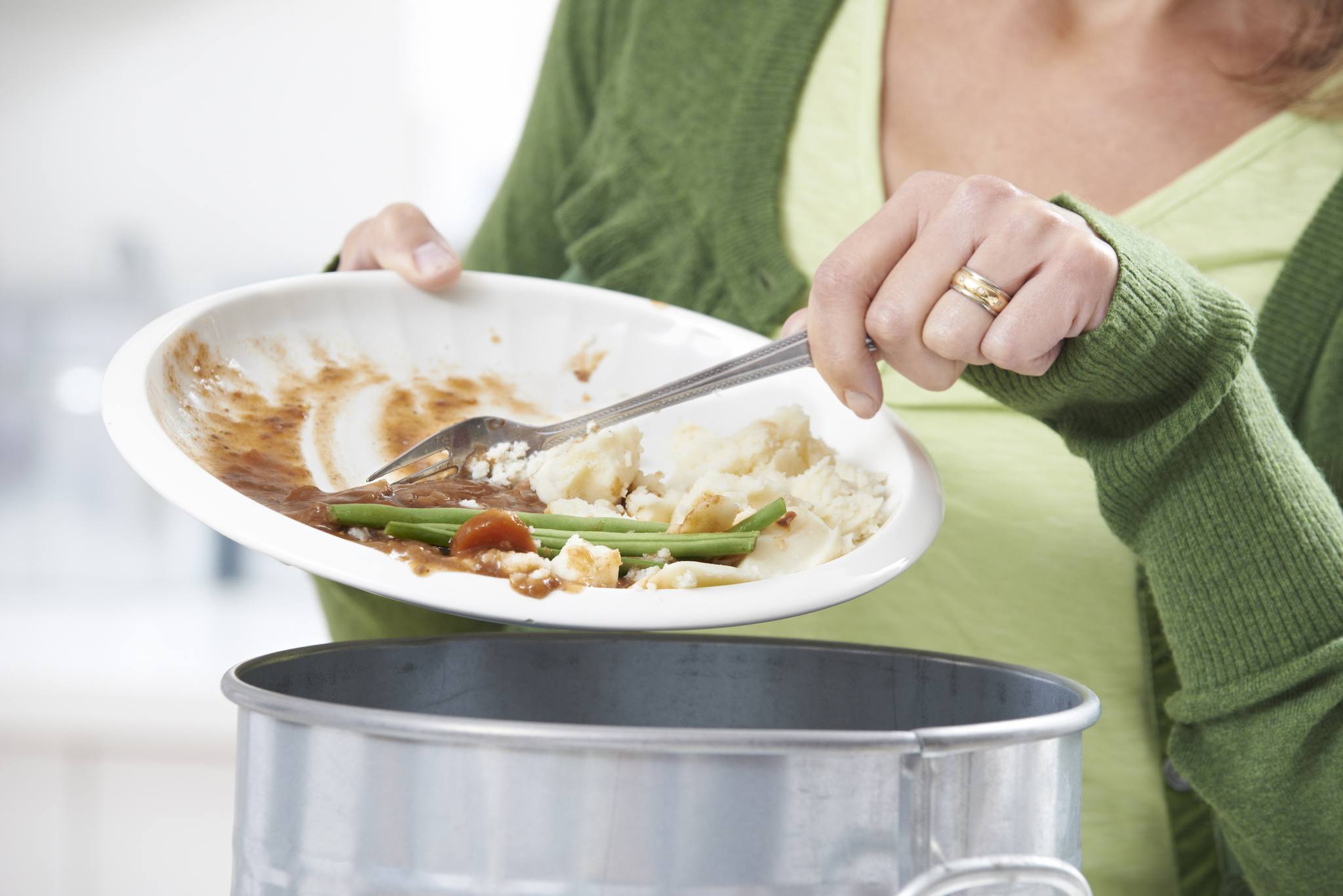 Woman Scraping Food Leftovers Into Garbage Bin