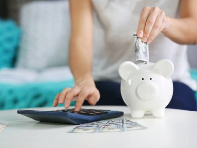 Millennial woman puts money in piggy bank