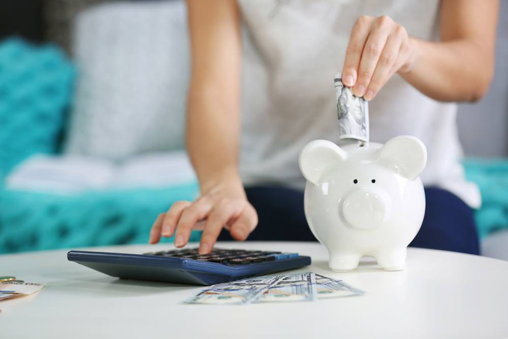 Millennial woman puts money in piggy bank