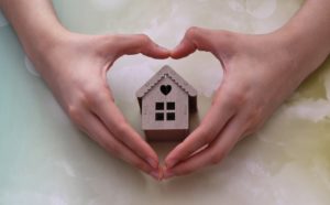 model house inside heart-shaped hands