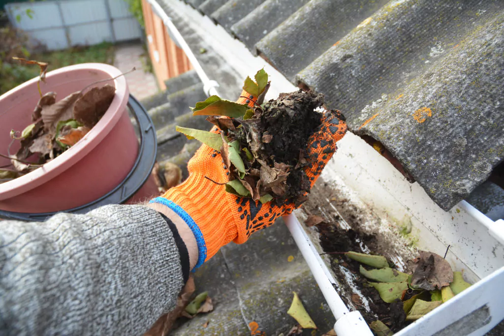 Man cleaning clogged gutter