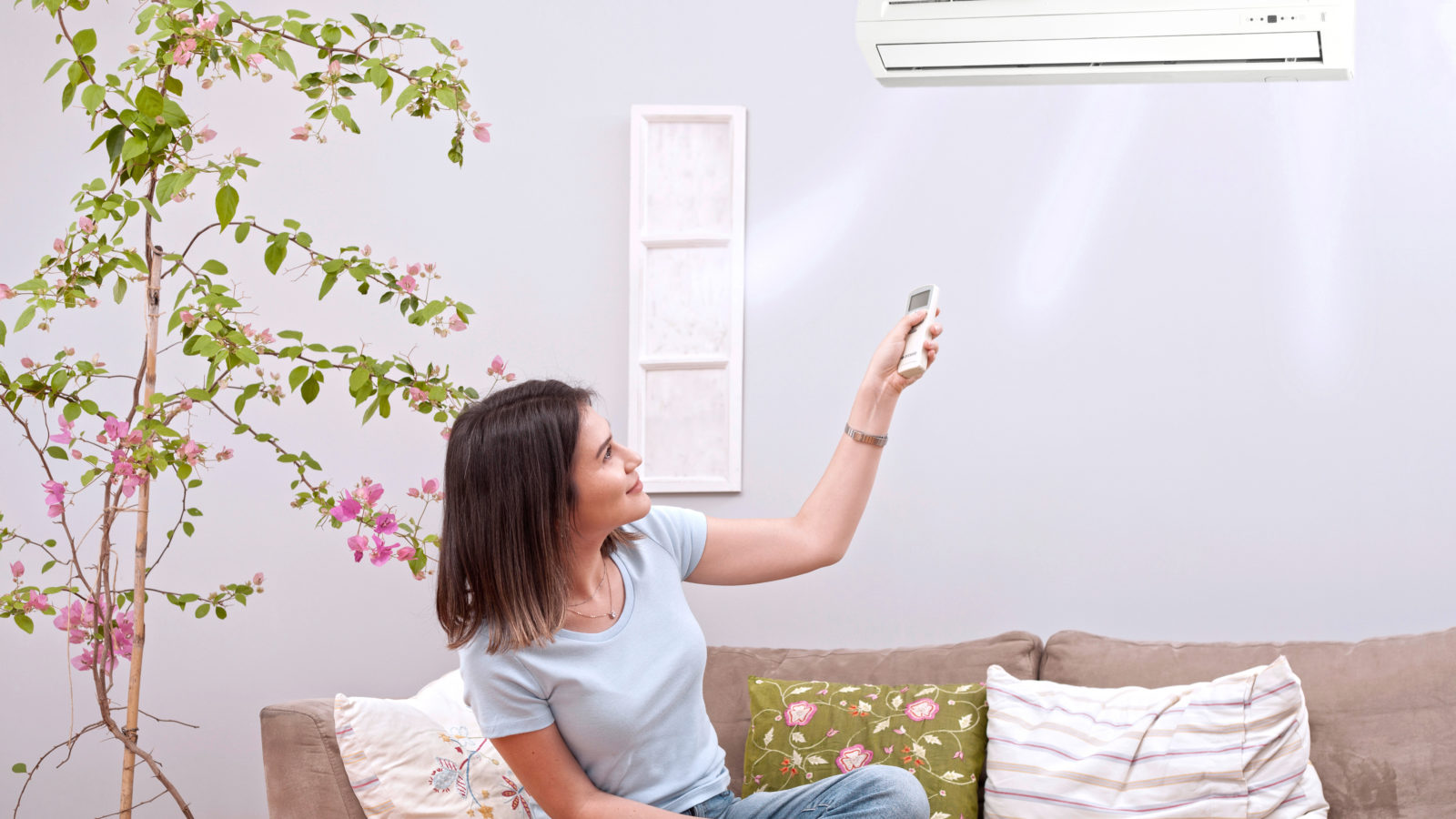 woman using remote control for air conditioner