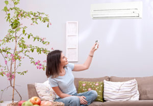 woman using remote control for air conditioner