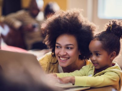 Mom watches child in a classroom use a computer