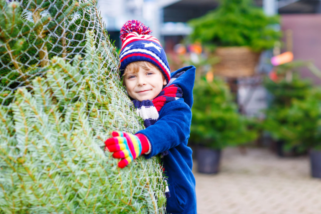 Small boy hugging a christmas tree