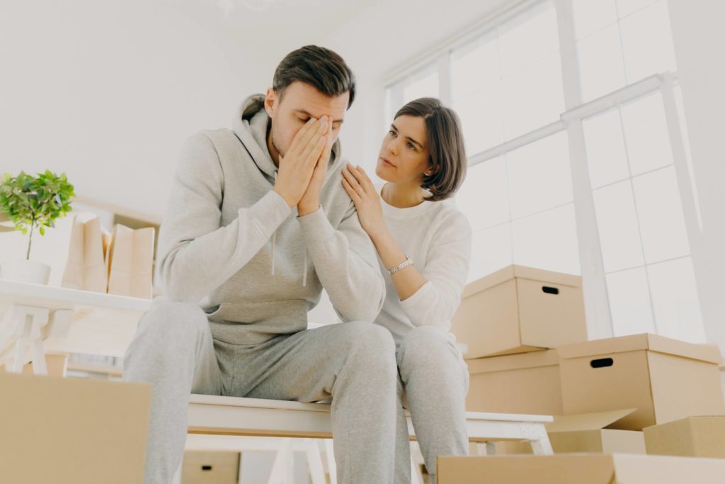 Husband and wife unhappy surrounded by moving boxes