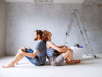 Millennial couple painting walls in their new house