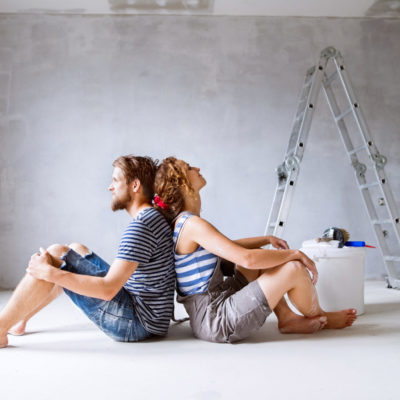 Millennial couple painting walls in their new house