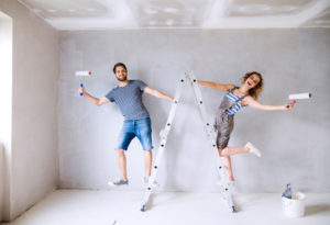 Couple on ladders painting walls