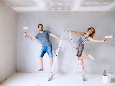 Couple on ladders painting walls