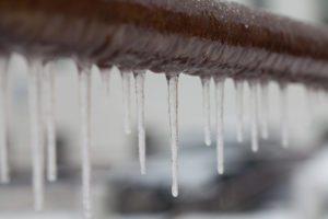 iIcicles hanging from a brown pipe. Frozen water and metal surface, winter time concept. selective focus shallow depth of field photo