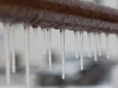 iIcicles hanging from a brown pipe. Frozen water and metal surface, winter time concept. selective focus shallow depth of field photo