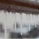 iIcicles hanging from a brown pipe. Frozen water and metal surface, winter time concept. selective focus shallow depth of field photo
