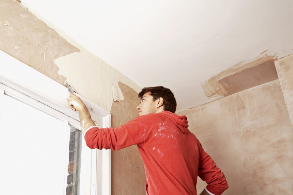 Man scraping paint off a wall