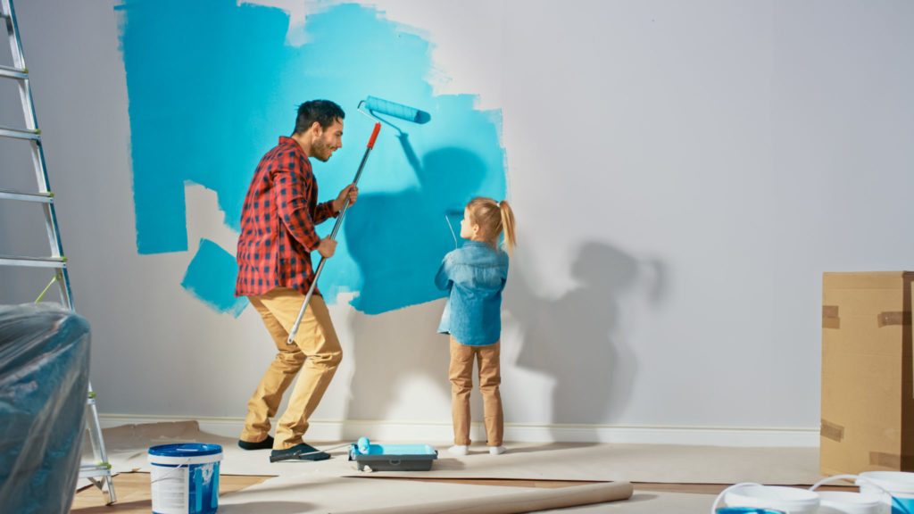 Father and daughter painting walls of a new home