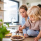 Young family with two small children indoors in kitchen, eating pancakes.