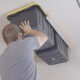 Man attaching garage storage bins to ceiling.