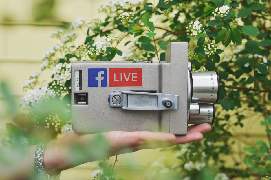 Hand holding a symbolic video camera in front of a home