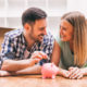 Young couple placing money in a piggy bank